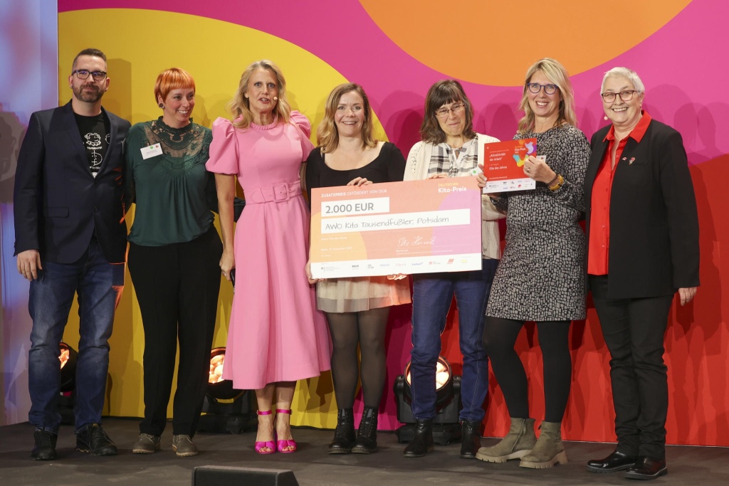 Gruppenbild mit Scheck über 2.000 Euro. Ein Mann und sechs Frauen stehen in einer Reihe, lächeln und 2 der Frauen halten den Preis-Scheck vor sich.